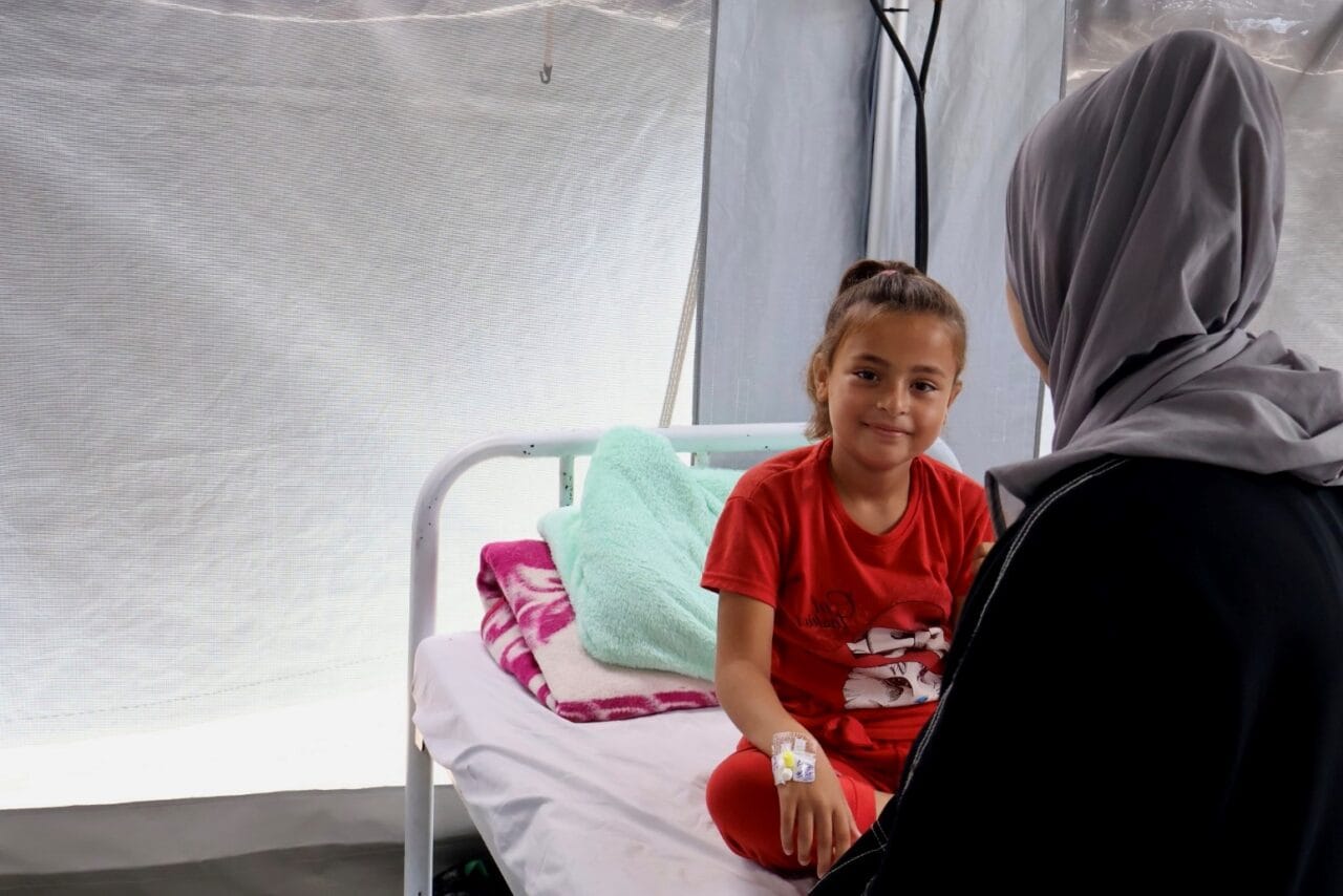 Hoidettavana oleva lapsi ja hänen äitinsä istuvat rauhallisina klinikan vuoteella Gazassa.