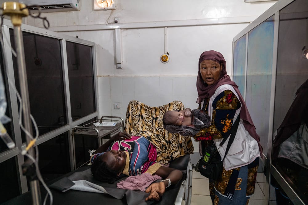 Työntekijämme pitelee käsissään vastasyntynyttä vauvaa. Hänen vieressään makaa juuri synnyttänyt henkilö. Tilanteessa on kiireen tuntu.