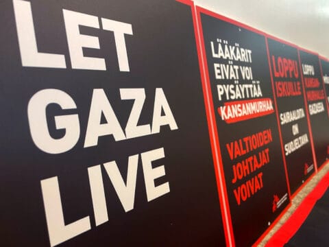 Mielenosoituskylttejä, joissa lukee let Gaza live ja lääkärit eivät voi pysäyttää kansanmurhaa, valtioiden johtajat voivat.