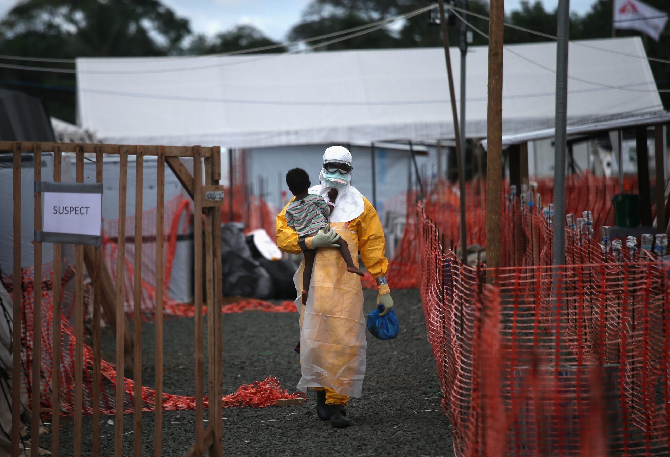 Työntekijä kantaa suojapuvussa ebolanhoitokeskuksessa lasta, jolla epäillään olevan ebola.